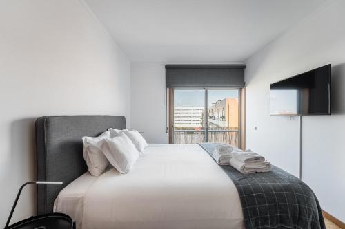1 dormitorio con 1 cama blanca grande y ventana en GuestReady - Urban hideaway near A Prainha Beach, en Vila do Conde