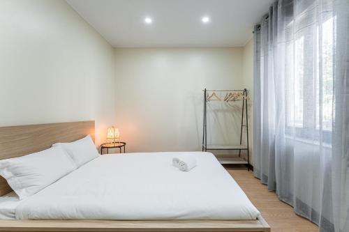 1 dormitorio con cama blanca y ventana grande en GuestReady - Sunny Family Apt with Private Terrace, en Oporto