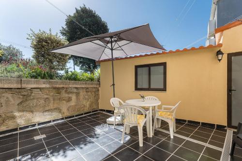 un patio con mesa, sillas y sombrilla en GuestReady - Sunny Family Apt with Private Terrace, en Oporto