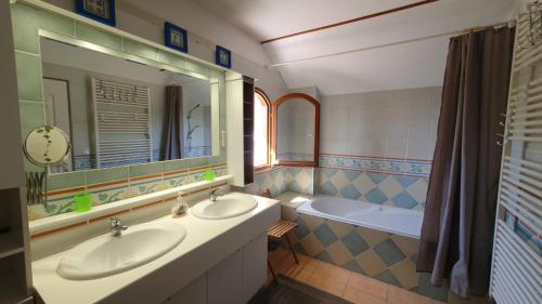 une salle de bain avec deux lavabos, une baignoire et un miroir dans l'établissement Lacustrebnb, à Choisy