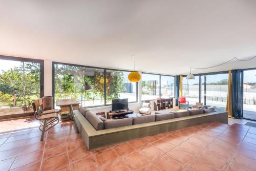 a large living room with a large couch and windows at GuestReady - Sunset Pool House in Esposende
