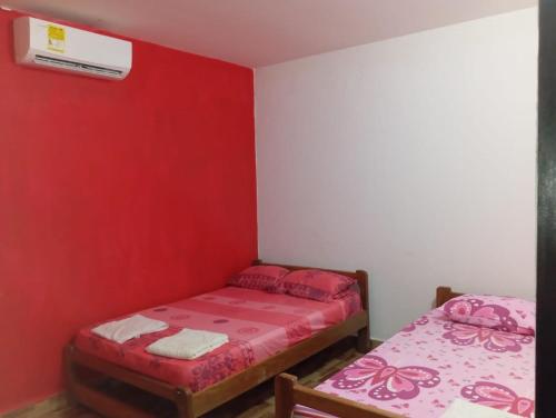 a room with two beds and a red wall at Villa del Carmen e hijos in San Antero