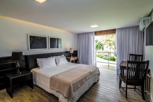 a bedroom with a bed and a desk and a window at Grande Hotel Canela in Canela