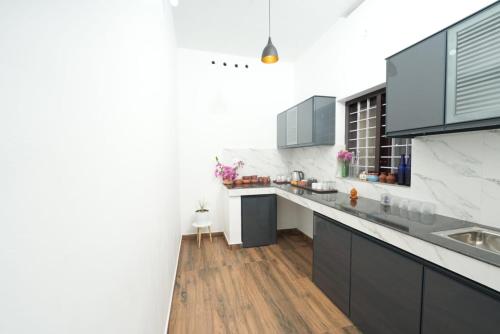 uma cozinha com paredes brancas e piso em madeira em VILLA MANTRAA em Varkala