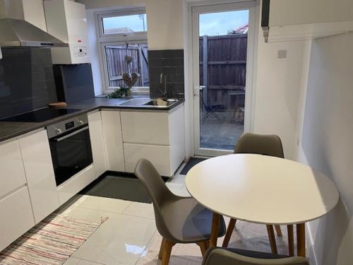 a kitchen with a white table and chairs and a table at Impeccable Holiday House in London Sleeps four in London