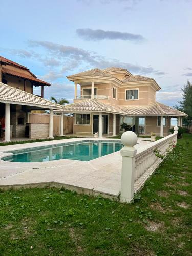 a large house with a swimming pool in the yard at Casa refúgio de paz in Cabo Frio
