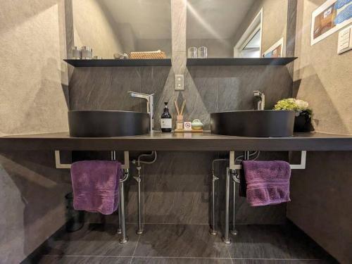 a bathroom with two sinks on a counter with purple towels at ホテル SHUNJU Dosse 1日1組様限定 in Kyoto