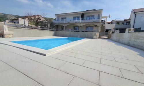 a swimming pool in front of a house at Apartmani Naomi&Leo in Senj