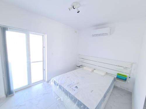 een witte kamer met een bed en een raam bij Top Floor with terrace and 5 mins walk to centre in Marsaskala