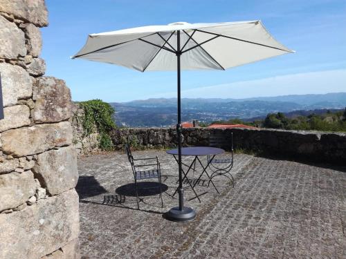 a table and chairs under an umbrella on a patio at Charming House in Andeviso with Mountain View in Arcos de Valdevez