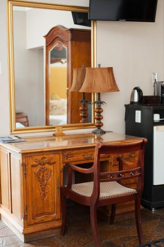 a wooden desk with a mirror and a lamp on it at Villa Brocant Guest house in Vryburg