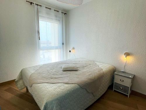 Un dormitorio blanco con una cama y una ventana. en T2+cabine, clim, parking privé, 4 pers, Le Barcarès - FR-1-81-430, en Le Barcarès