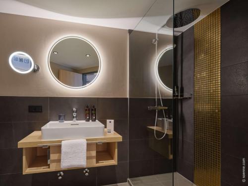 a bathroom with a sink and a mirror at Dorint Hotel Würzburg in Würzburg
