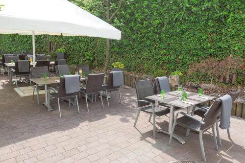 a group of tables and chairs under a white umbrella at Dorint Hotel Würzburg in Würzburg