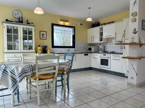 une cuisine avec des armoires blanches et une table et des chaises dans l'établissement 305 - Belle maison à deux pas de l'Anse du Croc, à Fréhel