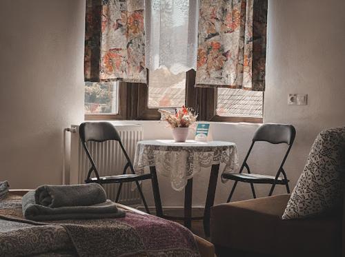 a living room with a table and two chairs and a table and a table at Casa Forrás in Borsec