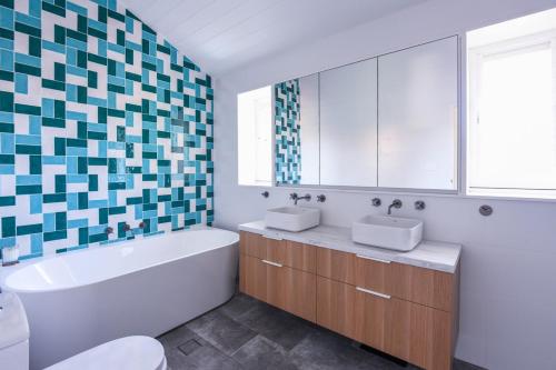 a bathroom with two sinks and a tub and a bath tub at Freshwater Villa - Seconds to the Beach in Freshwater