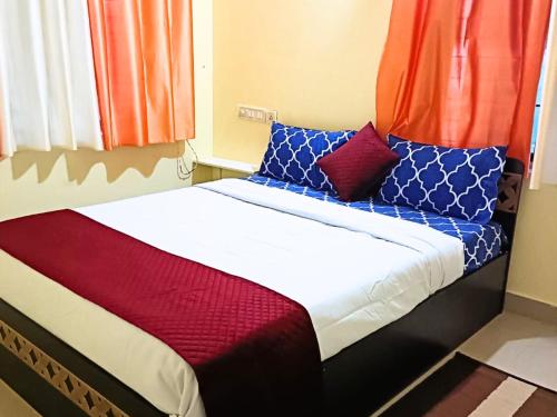 Una cama con almohadas rojas y azules. en Golden Magnolia Homestay en Bangalore