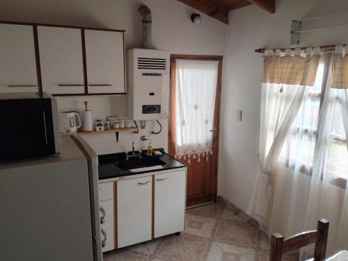 eine Küche mit weißen Schränken, einem Waschbecken und einem Fenster in der Unterkunft DonAldo in Ushuaia
