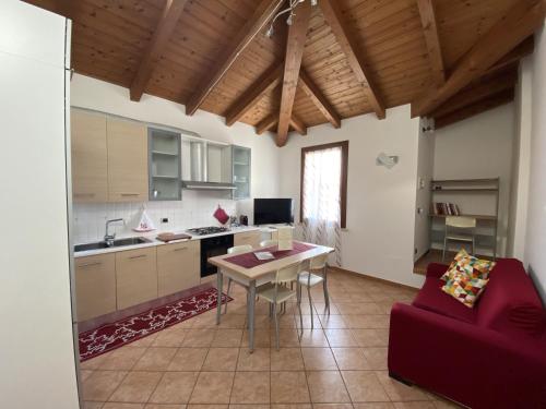 eine Küche und ein Wohnzimmer mit einem Tisch und einem roten Sofa in der Unterkunft Appartamento La Mansarda in Cerea