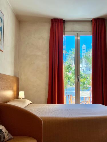 a bedroom with a bed and a window with red curtains at Acqua di Mare in Bordighera