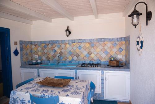 una cucina con tavolo, sedie blu e lavandino di La terrazza del sole “ apartments “ a Marettimo