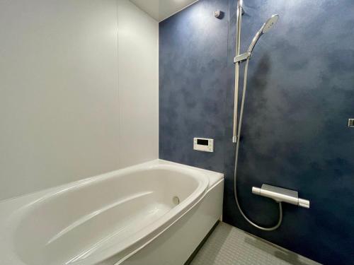 a bathroom with a white tub and a shower at Spruce Cottage in Yuzawa