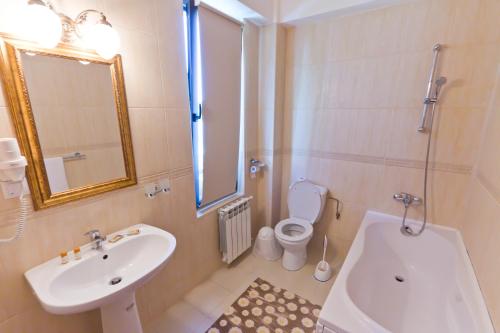 a bathroom with a sink and a toilet and a mirror at Vila Royal in Bacău