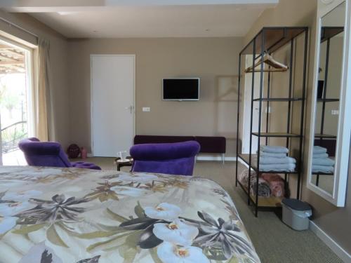 een slaapkamer met een bed en 2 paarse stoelen bij B & B de Pinguin in Bergentheim