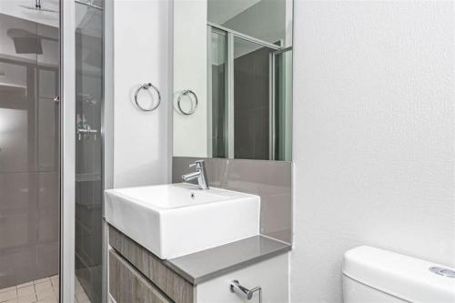 een witte badkamer met een wastafel en een spiegel bij OAM The View Morningside in Johannesburg