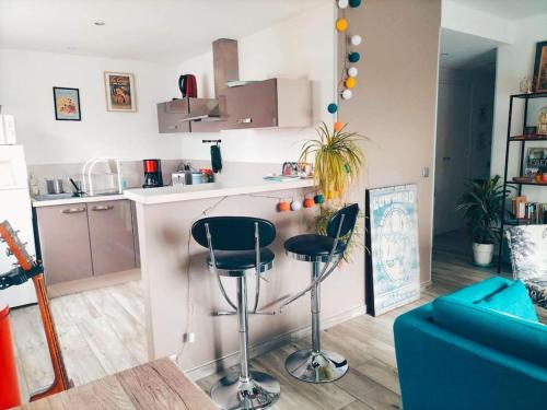 une cuisine avec deux tabourets de bar et un comptoir dans l'établissement Cozy apartment free parking CAEN, à Caen