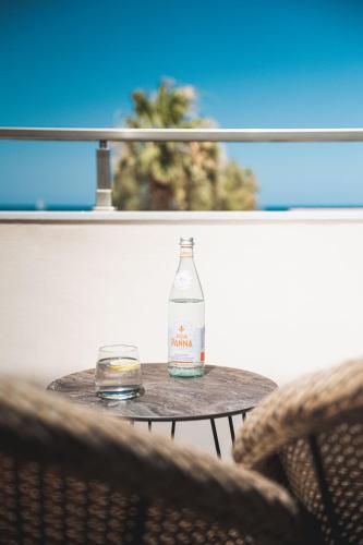 a bottle of water and a glass on a table at Palm Tree Beach Suites, by ZanteWize in Alykes