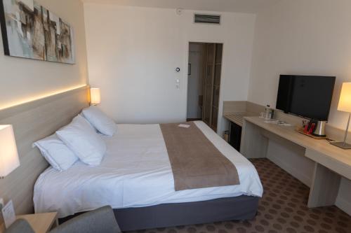a hotel room with a bed and a television at Best Western Plus Le Roof Vannes Bord de Mer in Vannes