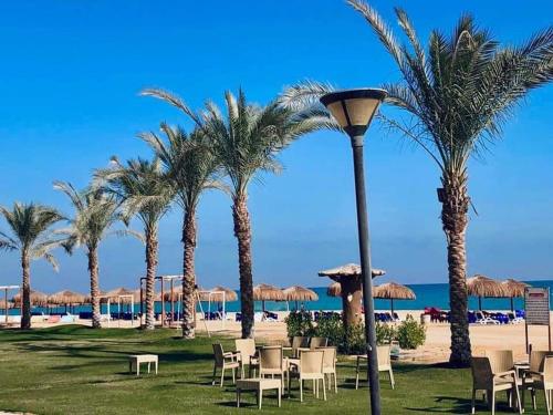 a beach with palm trees and chairs and a street light at LASIRENA PALM BEACH RESORT -FAMILY in Ain Sokhna