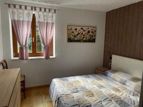 a bedroom with a bed and two windows at Villetta sulle dolomiti in Pracorno di Rabbi