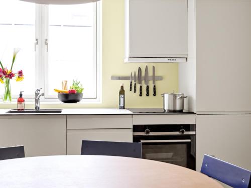 a kitchen with white cabinets and a table at BRIK Apartment Hotel in Copenhagen
