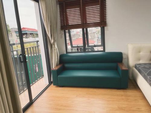 un sofá verde en una habitación con una ventana grande en Tropical land Little Hanoi apartment, en Hanói