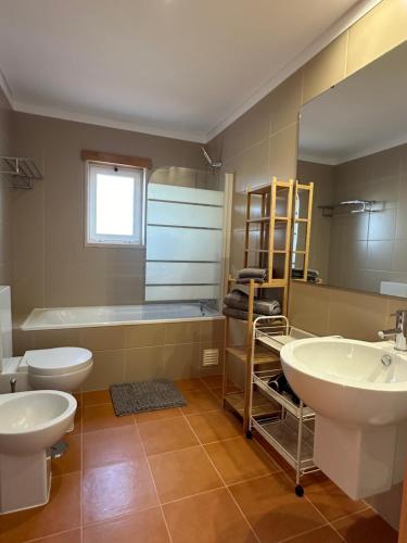 La salle de bains est pourvue de 2 lavabos, de toilettes et d'une baignoire. dans l'établissement Vila Noélia, à Albufeira