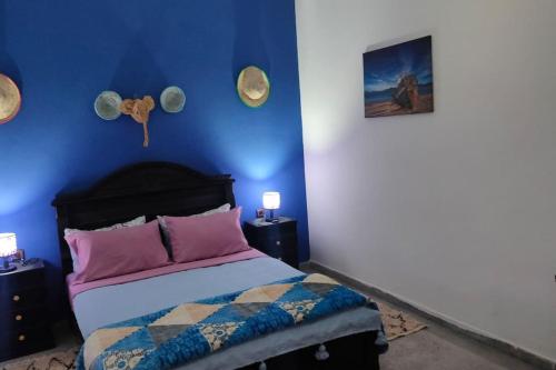 a bedroom with a bed with a blue wall at j appartement in Essaouira