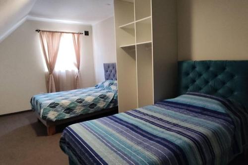 1 dormitorio con 2 camas y ventana en Cómoda casa en Talca, en Talca