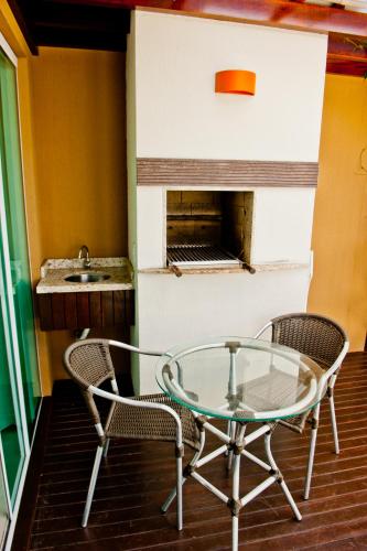 a glass table and two chairs and a sink at Pousada Bora Bora in Bombinhas