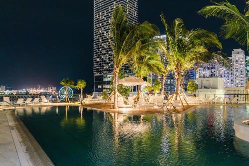 a pool with palm trees and a city at night at Gale Miami Hotel & Residences in Miami