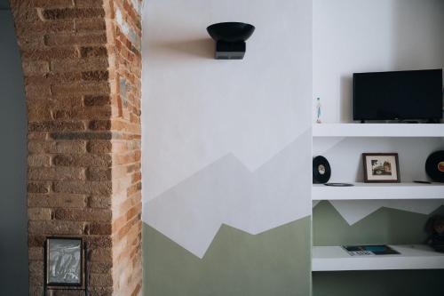 sala de estar con pared de ladrillo y TV en Casa di Clara in Piazza, ideale per smartworking, en Amandola