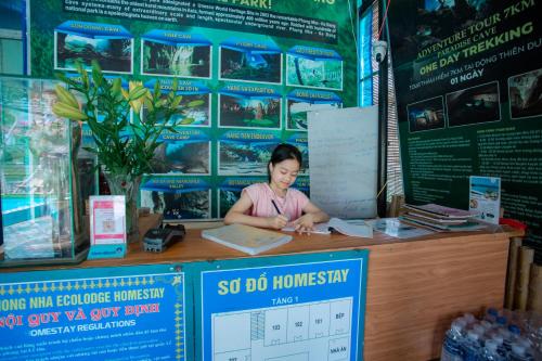 a woman sitting at a counter in a store at Phong Nha Ecolodge Homestay By HOFs in Phong Nha