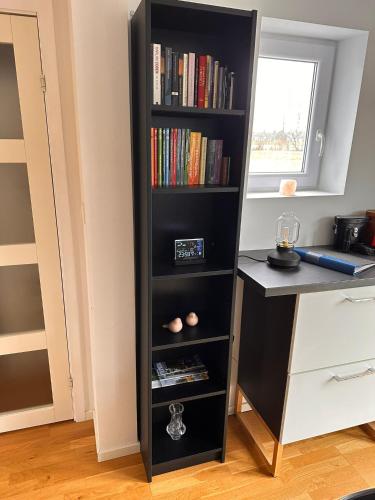 a black book shelf filled with books next to a desk at Stuga Fyra Säsonger - Fishing - Skiing - Hottub in Filipstad
