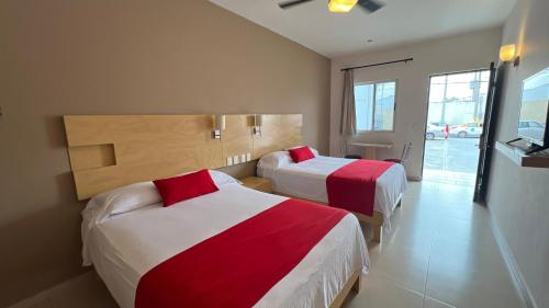 Cette chambre d'hôtel comprend 2 lits avec des draps rouges et blancs. dans l'établissement Nova Hotel, à Cadereyta Jiménez