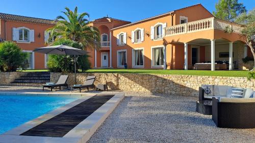 une grande maison avec une piscine devant dans l'établissement VILLA PALMIER avec PISCINE CHAUFFÉE PRIVÉE proche D'UZES ET ANDUZE, à Cannes-et-Clairan