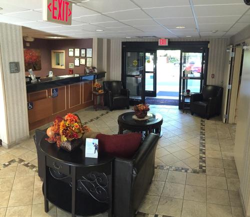 a lobby with a waiting room with a couch and tables at Hawthorn Suites by Wyndham Rancho Cordova/Folsom in Rancho Cordova