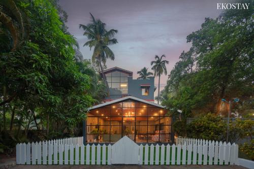 a house with a white picket fence in front of it at Ekostay Jungle Beach Villa I 1 Acre Property I 100 Meters from the Beach in Alibaug