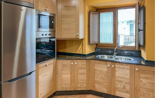 a kitchen with wooden cabinets and a stainless steel refrigerator at Cozy Apartment In O Porto De Espasante in Porto de Espasante